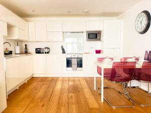 una cocina con armarios blancos y un reloj en la pared en Omega Terrace, Luxury Modern Interior, Located Close To Alexandra Palace en Londres