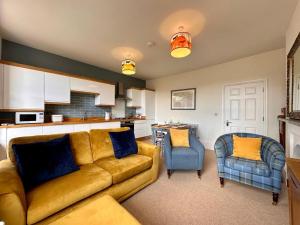 a living room with a yellow couch and a kitchen at Opera View by Together Travel - Stylish 2-Bedroom Apartment in Buxton