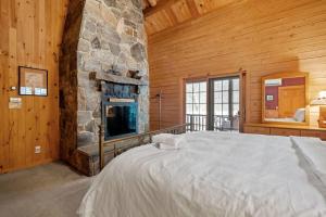 una camera da letto con un letto grande e un camino in pietra di Cozy Log Cabin on the River with Fireplace and Loft a Townshend