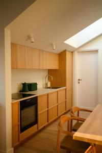 a kitchen with wooden cabinets and a table with chairs at Pine Attic - new & cozy 3 bedroom apartment,Nida in Nida