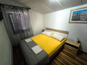 een kleine slaapkamer met een geel bed en een raam bij Apartmani Andrea in Pula