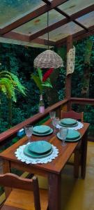 una mesa de madera con platos y vasos. en Morena Flor Cabana, en Angra dos Reis