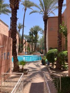 un resort con piscina circondata da palme di RIAD Lalla Aicha-Qariya Siyahia Marrakech a Marrakech