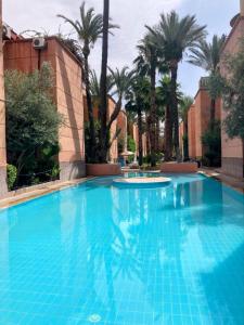 ein großer blauer Pool mit Palmen im Hintergrund in der Unterkunft RIAD Lalla Aicha-Qariya Siyahia Marrakech in Marrakesch