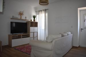 a living room with a white couch and a television at Casa da Espiga - Alentejo in Trigaches