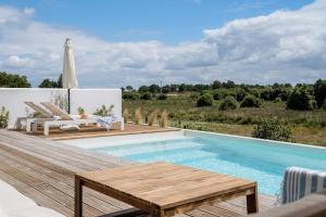 einen Pool mit einer Holzterrasse, einem Tisch und Stühlen in der Unterkunft Villa Possanco, Comporta beach villa in Comporta