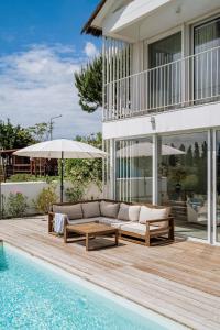 un sofá sentado en una terraza junto a una piscina en Villa Possanco, Comporta beach villa, en Comporta