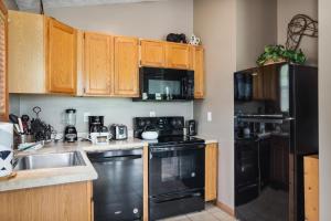 a kitchen with black appliances and wooden cabinets at Cozy Bear Hideaway By Stony Brook Cabins in Cosby
