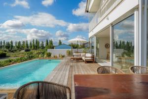 een patio met een tafel en stoelen en een zwembad bij Villa Possanco, Comporta beach villa in Comporta