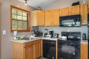 a kitchen with wooden cabinets and a sink and a stove at Cozy Bear Hideaway By Stony Brook Cabins in Cosby +15 photos