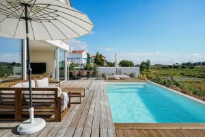 a house with a swimming pool and an umbrella at Villa Possanco, Comporta beach villa in Comporta