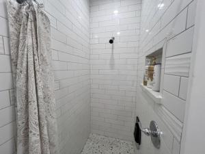 a white tiled shower with a shower curtain in a bathroom at ADA Friendly and AC Little House on the Ferry in Albany +16 photos