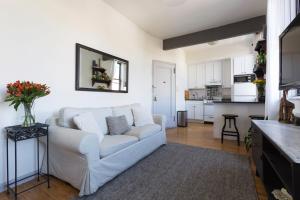 a living room with a white couch and a kitchen at Sunny Stylish West Village Condo in New York
