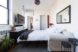 a white bedroom with a large bed and a tv at Sunny Stylish West Village Condo in New York +17 photos