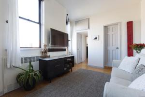 a living room with a tv and a white couch at Sunny Stylish West Village Condo in New York