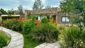 a garden with red flowers in front of a house at Chacras House in Chacras de Coria