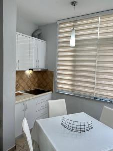 une cuisine avec une table et des chaises blanches ainsi qu'une fenêtre dans l'établissement Apartment 50m Away From The Beach, à Durrës