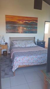 une chambre avec un lit et un tableau au mur dans l'établissement casa perfeita de sonho e completa, à Armacao dos Buzios