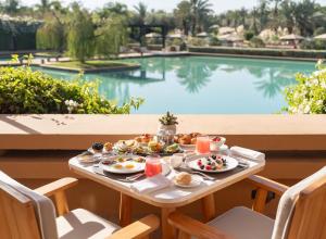 a table with breakfast food next to a swimming pool at Mandarin Oriental, Marrakech in Marrakech