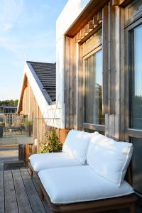 a white couch sitting on a wooden deck at Pine Attic - new & cozy 3 bedroom apartment,Nida in Nida
