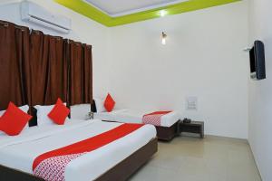 a bedroom with two beds with red pillows at OYO Hotel Shirdi Sai Inn in Shirdi