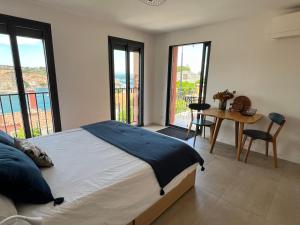 a bedroom with a bed and a table and windows at Canta la Mar - Vue exceptionnelle in Collioure