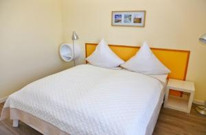 una camera da letto con un letto con lenzuola bianche e una lampada di Am Rundsteg 13 a Burgtiefe auf Fehmarn 