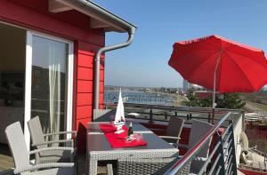 un tavolo con ombrellone rosso su un balcone di Am Rundsteg 13 a Burgtiefe auf Fehmarn 