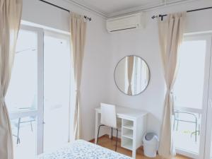 een slaapkamer met witte muren, een spiegel en een bureau bij Rooms and Apartments Robert in Rovinj