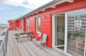 Casa roja con terraza de madera con mesa y sillas en Am Rundsteg 12, en Burgtiefe auf Fehmarn 