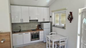 a kitchen with white cabinets and a table and a sink at Apartmani Natasa in Vantačići