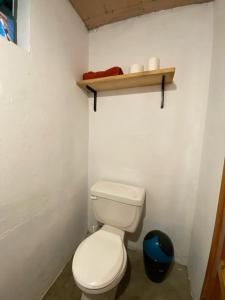 a bathroom with a white toilet and a wooden shelf at Casa los abuelos cerca de la playa los Salpores in Panajachel