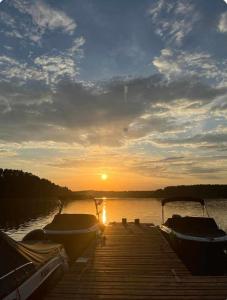 two boats are docked at a dock at sunset at Jagodzianka in Miłki +4 photos