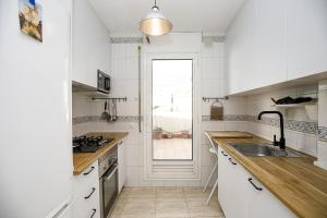 cocina con armarios blancos, fregadero y ventana en Apartamento con dos grandes terrazas en Girona, en Girona
