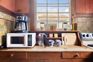 a kitchen with a microwave and a coffee maker on a counter at Breezy beach apt, steps to the sand! Full AC too - 18 Up in San Juan
