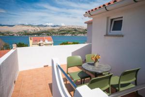 a balcony with a table and chairs and a view of the water at Apartments Andreja in Pag