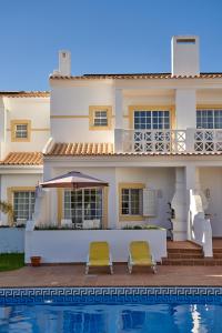 a house with two chairs next to a swimming pool at BALAIA PLAZA AL in Albufeira