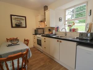 een keuken met witte kasten, een wastafel en een tafel bij Fordie East Cottage in Crieff