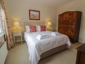 een slaapkamer met een wit bed en handdoeken bij Fordie East Cottage in Crieff