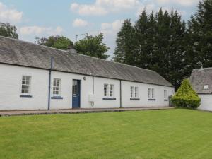 een wit gebouw met een blauwe deur en een tuin bij Fordie East Cottage in Crieff