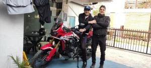 een man en een vrouw die naast een rode motor staan bij Blue Lake hostel in Ohrid