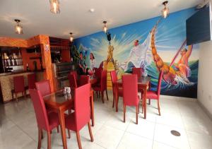 a dining room with red chairs and a painting on the wall at Hotel Korianka in Trujillo