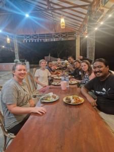 a group of people sitting at a table eating food at Asim Paris Guesthouse in Bukit Lawang