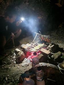 Un uomo sta cucinando cibo sul fuoco di Asim Paris Guesthouse a Bukit Lawang
