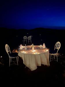 een tafel met twee stoelen en een tafel met een witte tafeldoek bij Camp M'hamid Ras N'khal in Mhamid