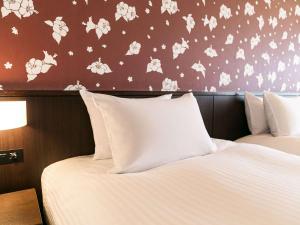 a bedroom with two beds and a wall with flowers at Grand Mercure Okinawa Cape Zanpa Resort in Yomitan