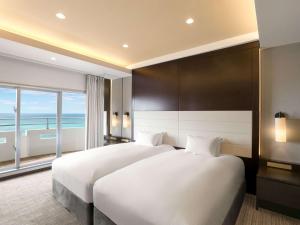 a bedroom with a large bed and a large window at Grand Mercure Okinawa Cape Zanpa Resort in Yomitan