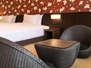 a hotel room with a bed and chairs and a table at Grand Mercure Okinawa Cape Zanpa Resort in Yomitan