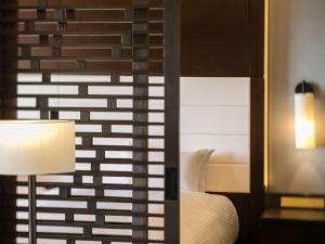 a bedroom with a bed and a lamp and a mirror at Grand Mercure Okinawa Cape Zanpa Resort in Yomitan