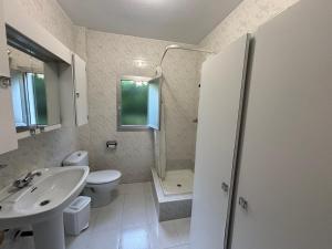 Baño blanco con lavabo y aseo en Casa Finca Patelo, en Bergondo